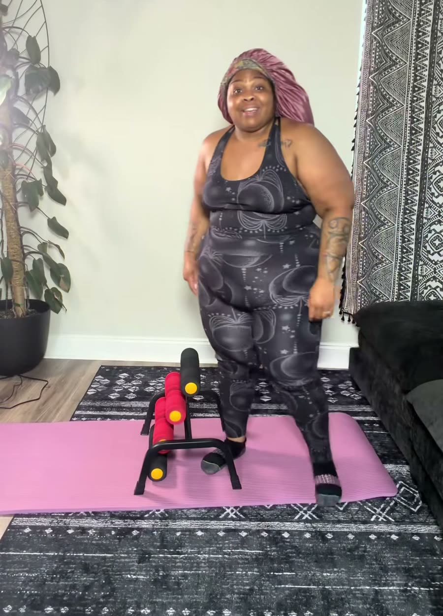 A plus-size woman standing next to her Elva decompressor on the mat at home