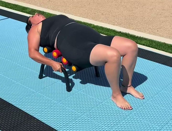 A woman lying back on the Elva outside by the pool